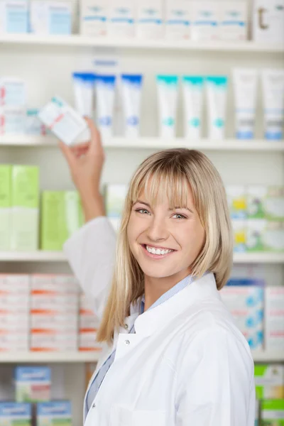 Kvinnliga farmaceut tar medicin låda från hyllan — Stockfoto