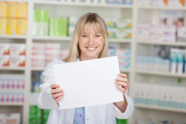 Female pharmacist showing white paper — Stock Photo, Image