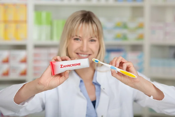 Farmacista che tiene dentifricio e spazzolino da denti — Foto Stock
