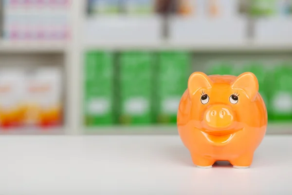 Orange piggy bank on pharmacy counter — Stock Photo, Image