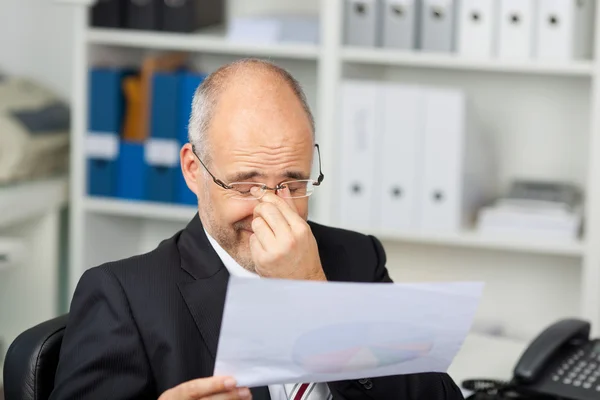 Affärsman som innehar dokument samtidigt gnugga ögonen — Stockfoto