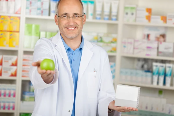 Pharmacist showing green apple — Stock Photo, Image