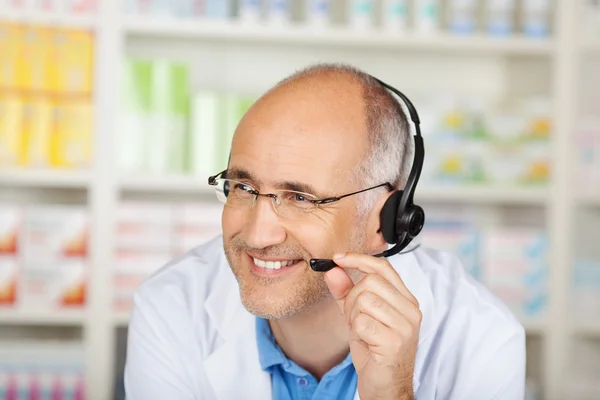 Farmacéutico conversando sobre auriculares en farmacia — Foto de Stock