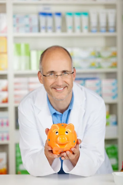 Farmacêutico segurando banco porquinho — Fotografia de Stock