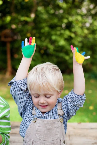 Liten pojke med färgglada målade händer — Stockfoto