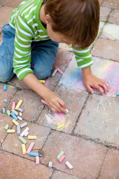 Boy playing with chalk on pavement — Stock Photo, Image