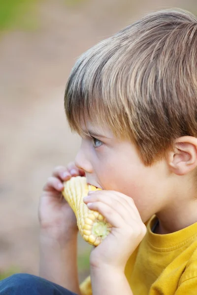 Pojken äta majs på cob — Stockfoto