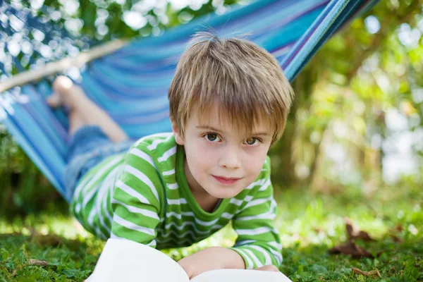 Niño acostado en una hamaca y leyendo un libro — Foto de Stock