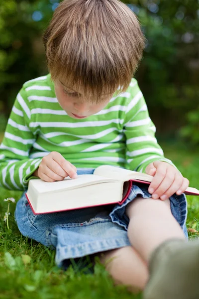 Liten pojke läser med fingret på bok — Stockfoto