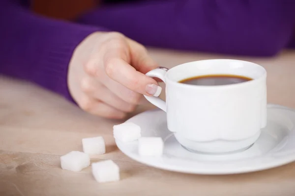Zákazníka ruka s šálek kávy a kostky cukru u stolu — Stock fotografie