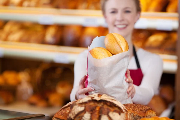 Bäckereiangestellte hält Tüte mit Brot — Stockfoto