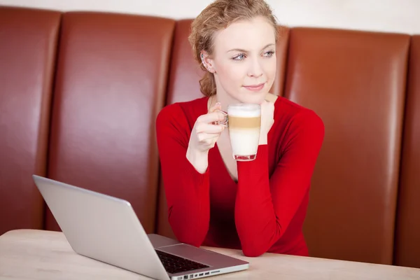 Femme avec ordinateur portable rêvant dans un café — Photo