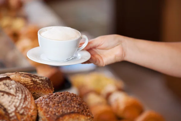 Travailleur de boulangerie servant du cappuccino — Photo