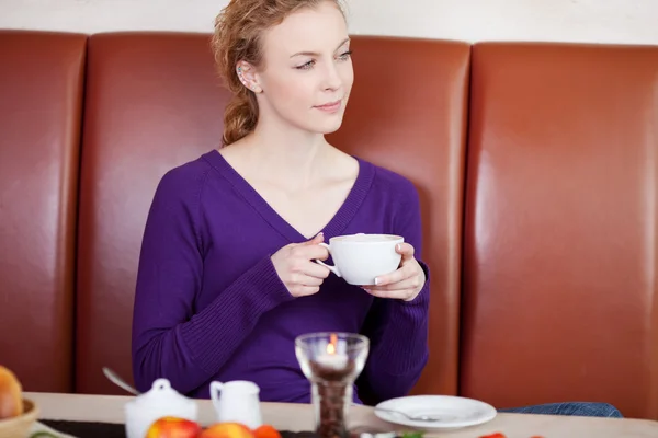 Mujer sosteniendo la taza de café mientras mira hacia otro lado — Foto de Stock