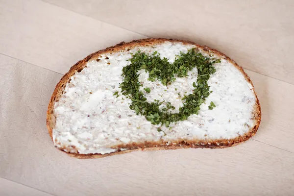 Brot mit Käse-Creme-Aufstrich und Herz aus Kräutern — Stockfoto