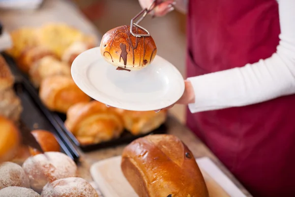 Padaria trabalhador mantendo o pão na placa — Fotografia de Stock