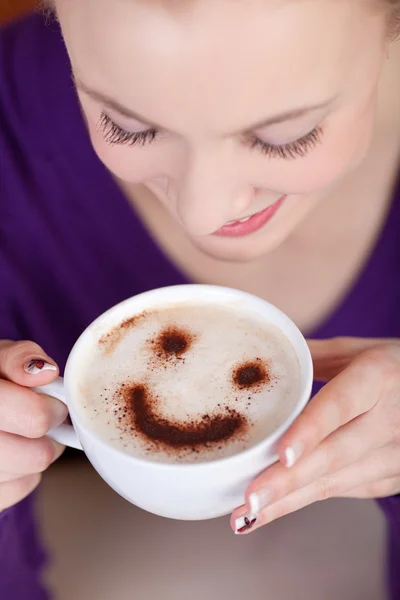 Woman enjoying cappuccino with a smile — Stock Photo, Image