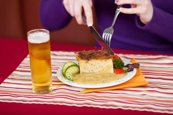 Frauenhände schneiden köstliche Mahlzeit mit Gabel und Messer am Tisch — Stockfoto