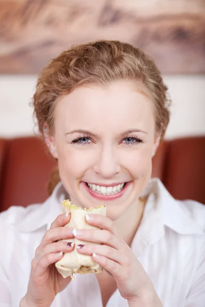 Sorrindo loira mulher comer envoltório — Fotografia de Stock