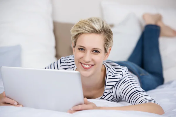 Mulher segurando tablet digital enquanto deitada na cama — Fotografia de Stock