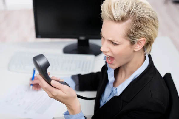 Mujer de negocios gritando en el receptor de teléfono en el escritorio —  Fotos de Stock