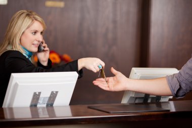 Young Receptionist Giving Room Keys To Customer clipart