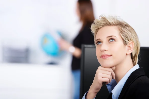 Задумчивая деловая женщина смотрит вверх в офисе — стоковое фото