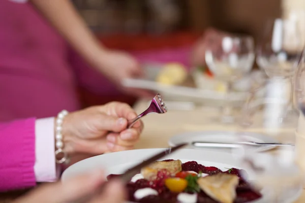 Женщина держит вилку и нож с тарелкой на столе ресторана — стоковое фото