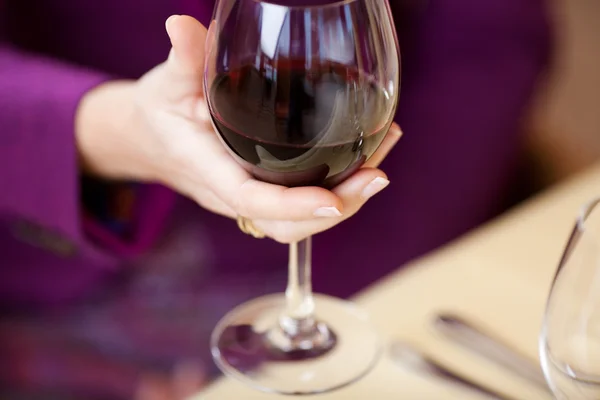 Hand hält Weinglas am Restauranttisch — Stockfoto