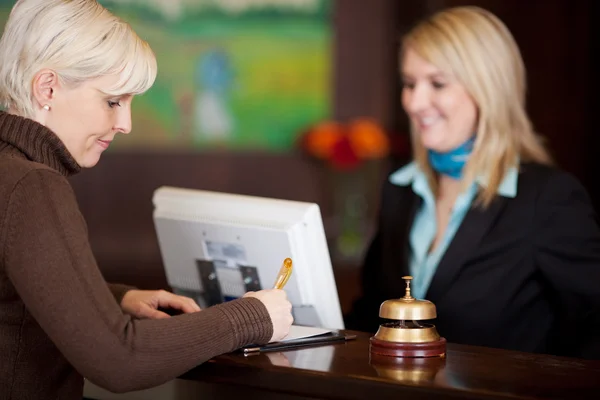 Guest filling up a formular at hotel counter — Stock Photo, Image