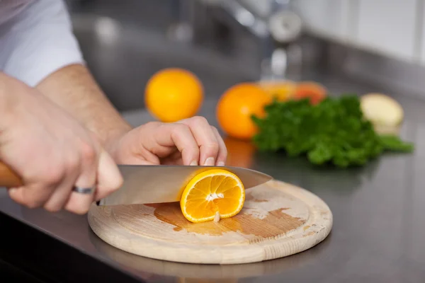 Cook cutting orange for dessert — Stock Photo, Image