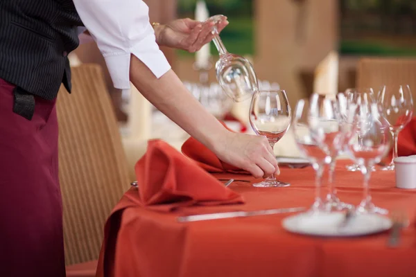 Serveerster schikken wijnglazen op tafel — Stockfoto