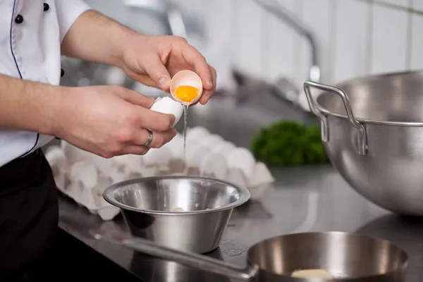 Chefs mãos derramando ovo na tigela — Fotografia de Stock