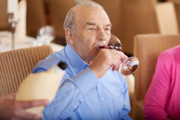 Sénior bebendo um copo de vinho tinto no restaurante — Fotografia de Stock