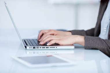 Woman typing on her laptop clipart