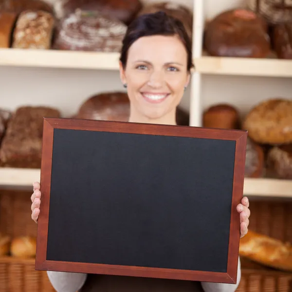 Bakery worker holding a blank chalkboard — Stock Photo, Image