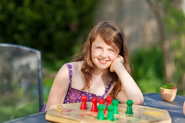 Mädchen spielt Ludo am Tisch im Park — Stockfoto