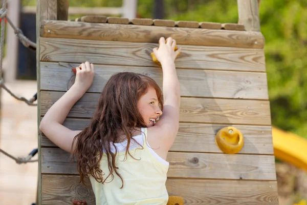 Giovane ragazza arrampicata parete al parco giochi — Foto Stock