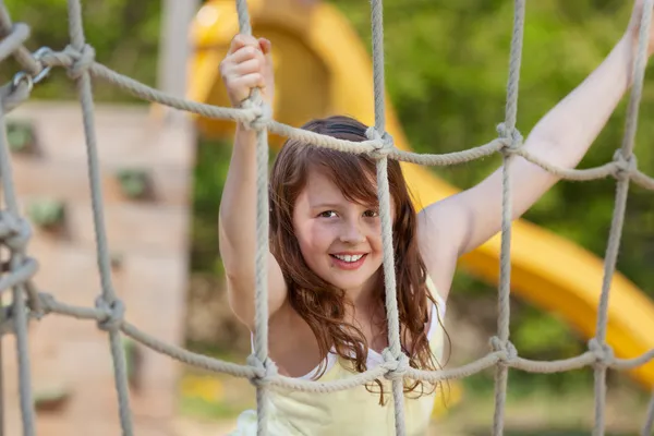 Girl climbing on a net at playground — Stock Photo, Image