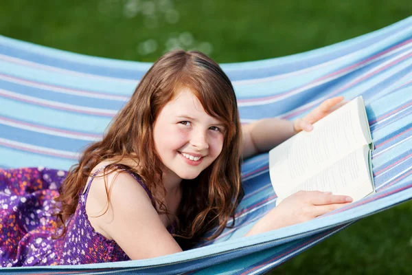 Meisje met boek liggend op de hangmat in park — Stockfoto