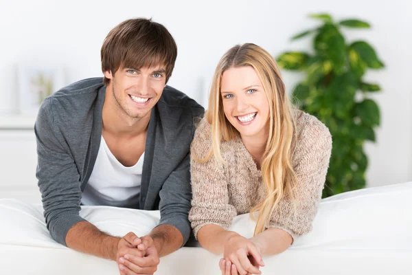 Sorrindo jovem casal inclinando-se no sofá — Fotografia de Stock