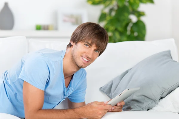 Man lying on sofa reading tablet — Stock Photo, Image