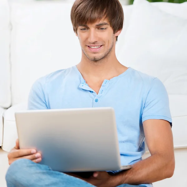 Homem feliz sentado no sofá com notebook — Fotografia de Stock