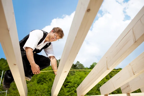 Happy carpenter measures beams with folding ruler — Stock Photo, Image