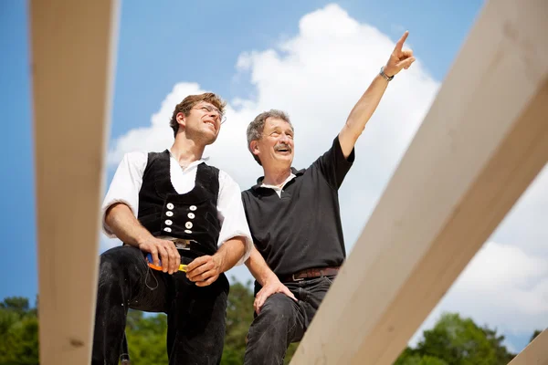 Dos carpinteros discutiendo el trabajo en el tejado —  Fotos de Stock