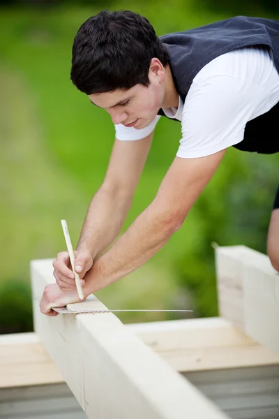 Carpenter making markings on a roof beam — Stock Photo, Image