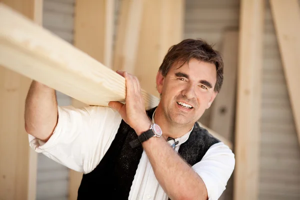 Carpenter carrying a large wood plank — Stock Photo, Image