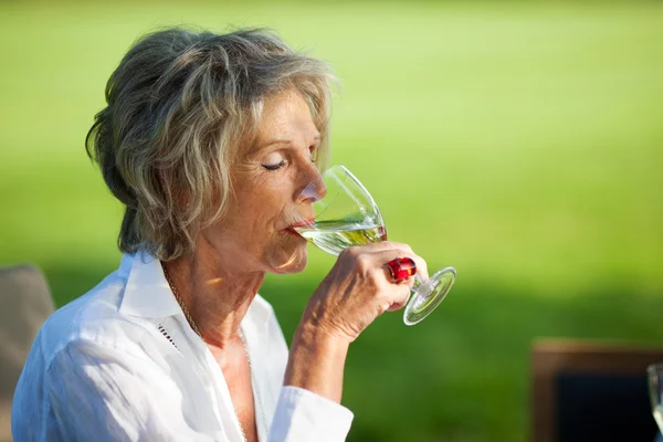 Idosa bebendo vinho com olhos fechados — Fotografia de Stock