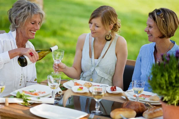 Vrouw gieten van wijn in glazen voor dochter aan eettafel — Stockfoto
