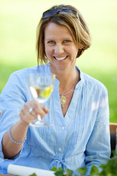 Reife Frau hält Weißwein im Rasen — Stockfoto